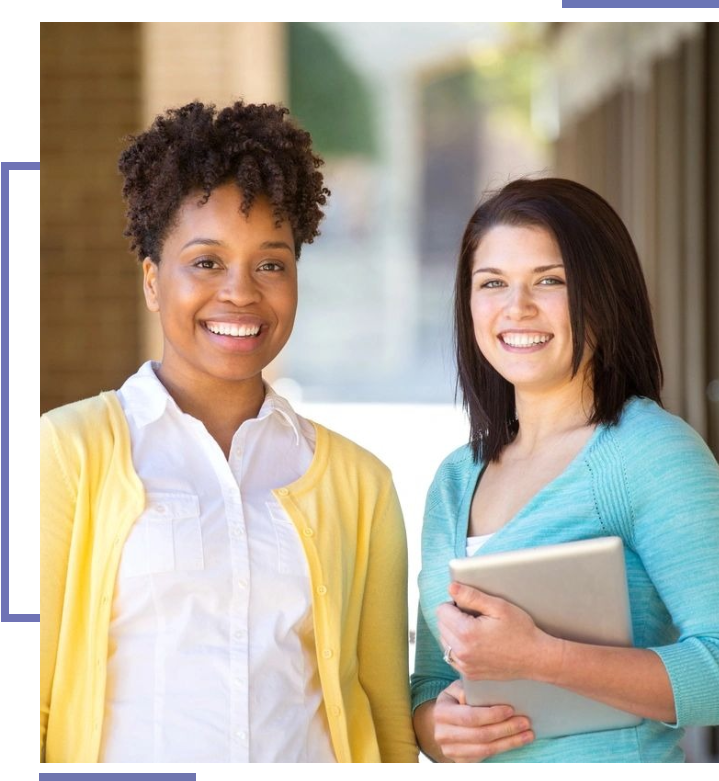 Two women standing next to each other holding a tablet.